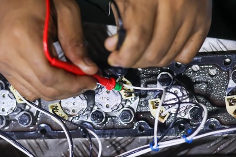 Mechanic testing electrical wiring connections with a multimeter