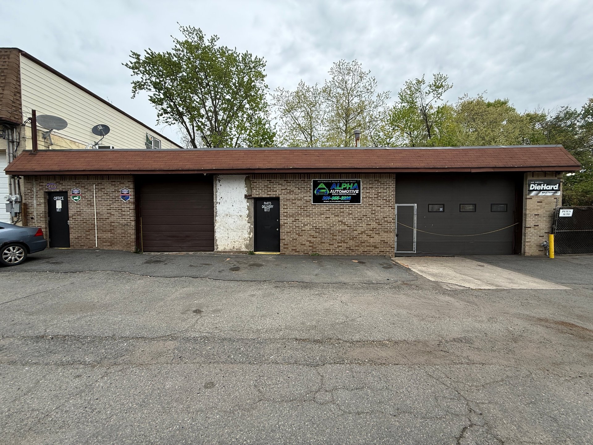 Single-story brick commercial building with multiple garage doors and service entrances, surrounded by bare pavement
