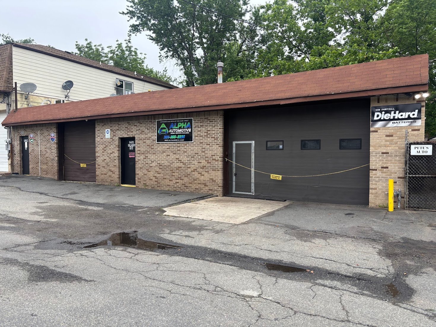 Brick commercial building with red roof, large garage door, and Diehard sign on exterior wall
