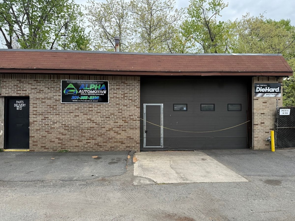 Front view of a brick automotive repair shop with a large dark garage door and signage on the facade